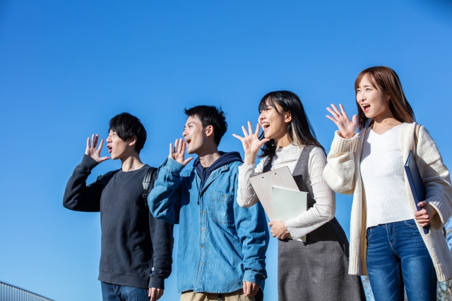 青空に向かって声を届ける若い世代の４人